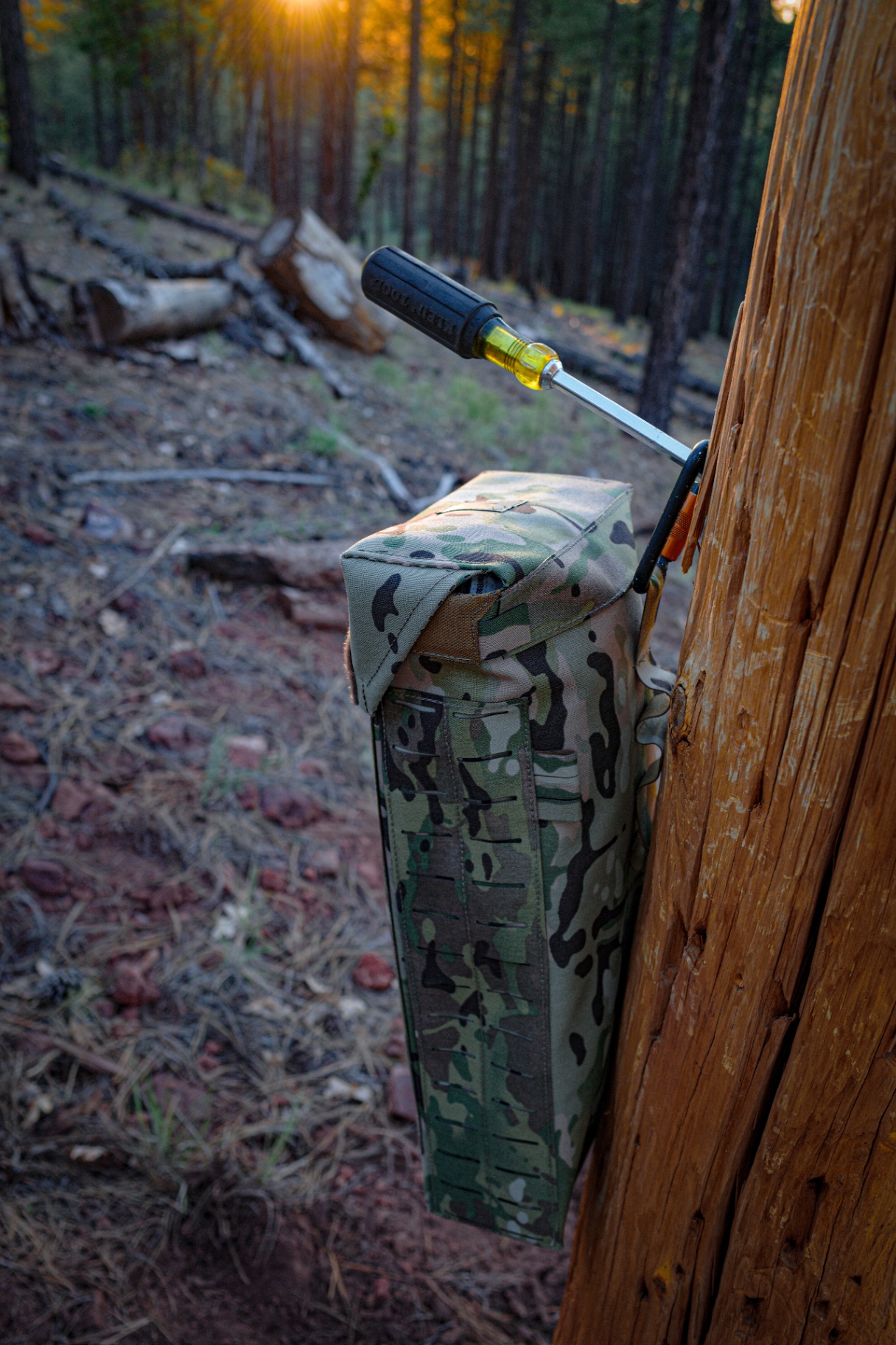 MultiCam glove bag carabinered to a utility pole with a Klein screwdriver stowed in the MOLLE