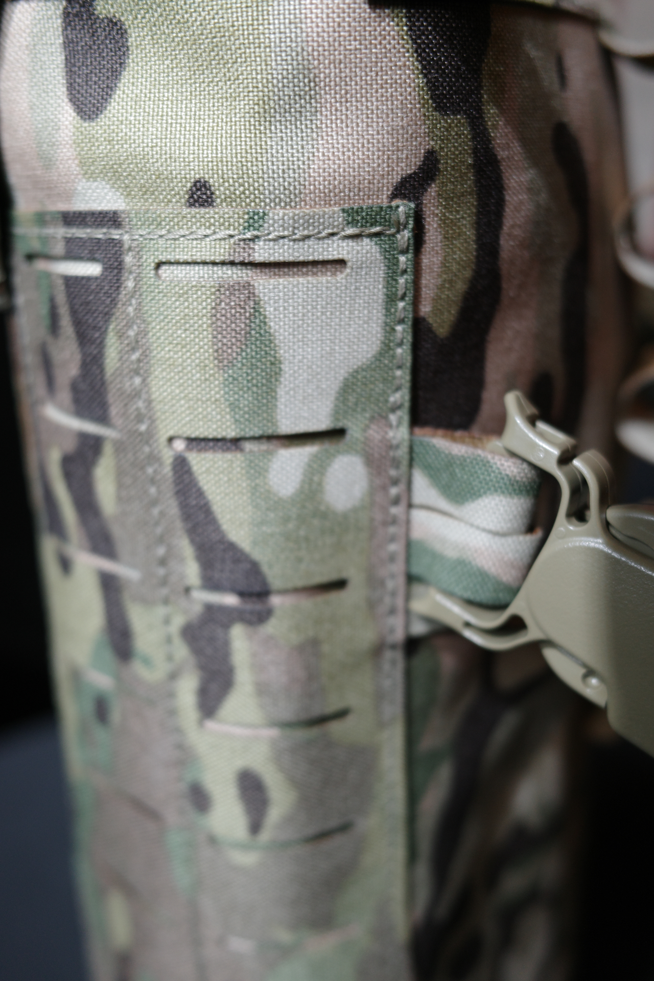 Macro detail of laser-cut MOLLE webbing and Ranger Green buckle on MultiCam fabric